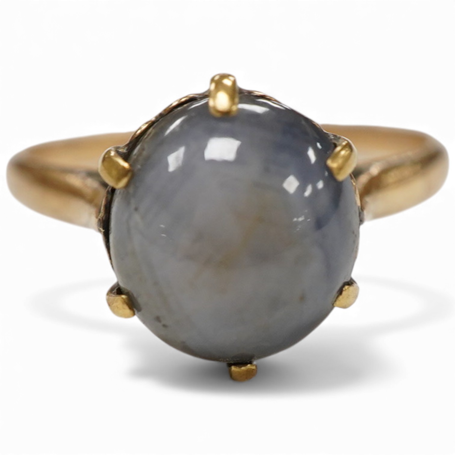 A yellow metal and single stone claw set star sapphire ring, size P, the stone approx. 9mm in diameter.